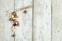 Macadamia nuts with a brown paper label on a wooden background (top view)