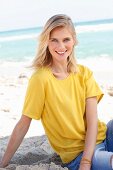 A blonde woman wearing a yellow T-shirt and jeans on the beach