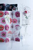Paravent mit Blumenstoff bezogen, weisser Designerstuhl aus Metall, Garderobenbaum und Vogelkäfig