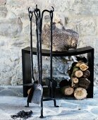 Firewood below black modern stool behind rustic set of fire irons