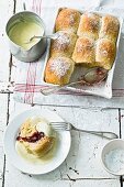 Sweet rolls made of yeast dough, filled with berry jam and served with custard