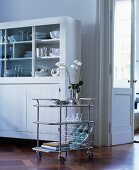 Elegant serving trolley next to white dresser