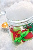 Small wrapped gifts in snow-covered mason jar
