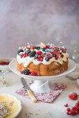 Vanilla bundt cake with cream cheese icing and berries on a cake stand