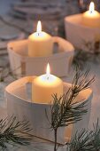 Lit candles in chip wood baskets and fir sprigs decorating table