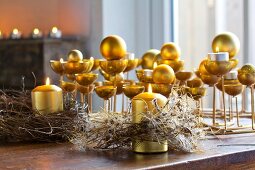 Goldfarbene Kerzenständer mit Kerzen und Kugeln und rustikale, getrocknete Kränze