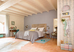 Schlafzimmer in Pastelltönen mit Doppelbett und Holzbalkendecke in französischem Landhaus