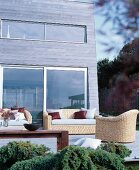 Comfortable wicker furniture on wooden terrace adjoining wood-clad façade