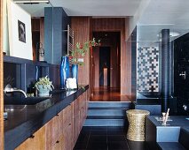 Washstand with charcoal-grey counter and wooden front in elegant bathroom