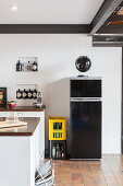 Schwarzer Kühlschrank vor weißem Mauerwerk in der Küche