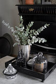 Black and white china pot next to silver vase on wooden tray