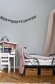 Garland of lettering on grey wall above bed and dolls' house