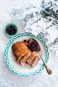 Duck breast with cranberry sauce on a plate in the snow at Christmas