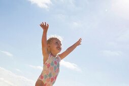 Blue sky and a little girl wearing a swimming costume