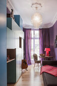 Blue cabinets in small guest room with purple walls