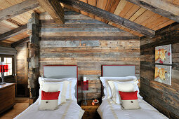 Twin beds in rustic bedroom with wooden walls