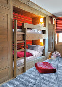 Transparent chair in front of fitted bunk beds with red striped back wall