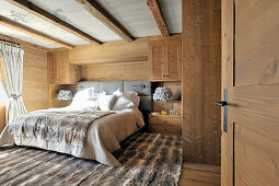 Rustikales Schlafzimmer mit Fellteppich und Holzverkleidung