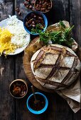 Ein Laib dunkles Sauerteigbrot mit Zutaten zum Füllen