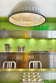Metal ceiling lamp in stainless steel kitchen with bright green wall