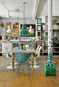 Stainless steel kitchen against white brick wall and dining table with classic chairs