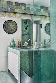 Washstand covered in green mosaic tiles in bathroom