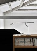 Designer desk lamp on magazine shelves next to black solid balustrade in loft apartment