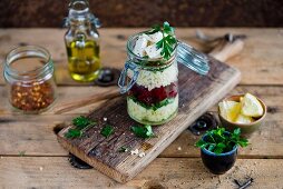Millet and feta salad with beetroot and parsley in a glass jar