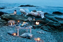 Candle lantern, lounger and cushions for romantic picnic by the sea