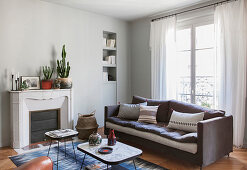 Sofa below window and disused fireplace in living room