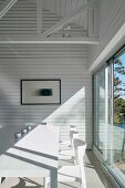 Light falling on dining table through large window below exposed roof structure