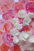 Röschen aus Papier auf gemaltem Blütenmeer