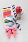 Origami bow and flower on paper with stripes of colour