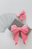 Pink origami bow on gift wrapped in polka-dot paper