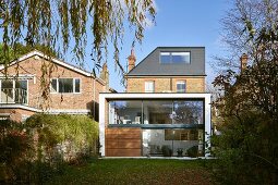 Moderner Erweiterungsbau an traditionelles Ziegelhaus mit Garten