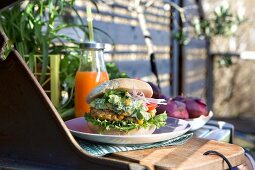 A chicken burger with a panko crust, avocado cream and salad on a table outdoors