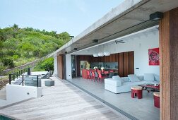 View into modern house with open wall adjoining terrace