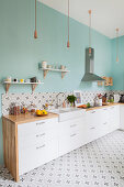 White cupboards, pale blue wall and patterned cement tiles in kitchen