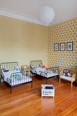 Kinderzimmer mit zwei Einzelbetten und tapezierter Wand in Altbauwohnung