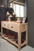 Wooden console table with two drawers and shoe rack below mirror on dark foyer wall