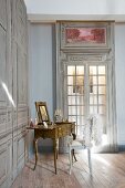 Feather boa draped over chair backrest next to antique dressing table