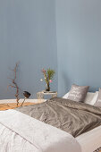 Double bed and side table in bedroom with blue walls