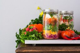 Two layered salads in glass jars with spinach, beans, cheese and eggs