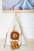 Small cloth lion in front of teepee on top of cabinet in child's bedroom