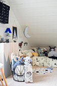 Animal soft toys in wire basket in front of cabinet in child's attic bedroom