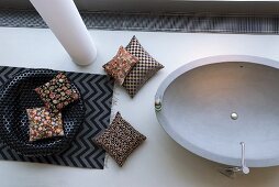 Mixture of patterns on cushions and rug next to oval bathtub