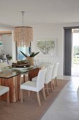 Dining table with glass top and white upholstered chairs in front of terrace door