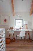 Desk in bright work area below window in attic room