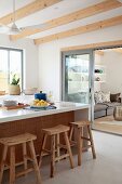 Rustic bar stools at white kitchen counter with view into living area