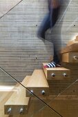 Person walking down floating staircase with glass balustrade